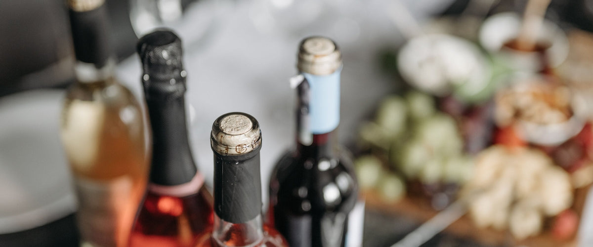 Unsere Neuheiten: Flaschenhälse von Rosé, Schaum- und Rotwein vor Käseplatte
