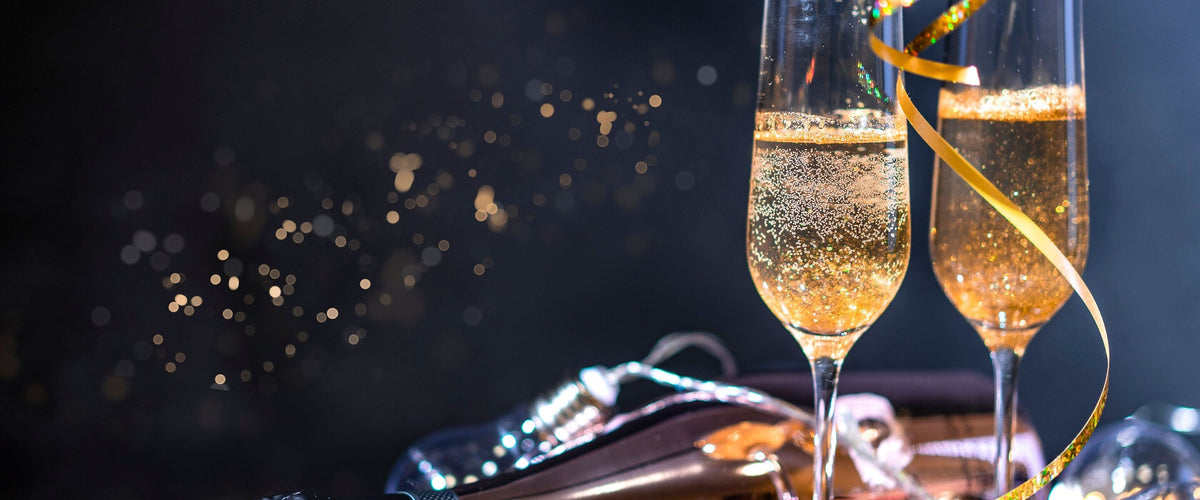 Sekt: Zwei Sektflöten mit goldenem Band im Lichterglanz