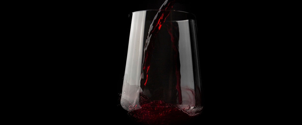 Cabernet Sauvignon: Rotwein fließt ins Glas, schwarzer Grund