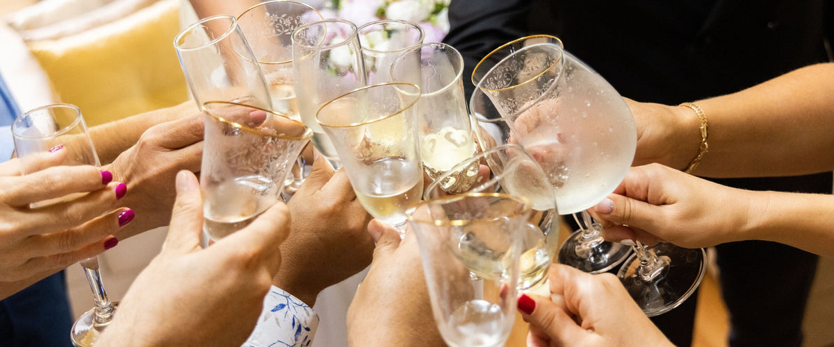 Champagner: Viele Hände stoßen mit Sektflöten an, festlicher Anlass, keine Gesichter