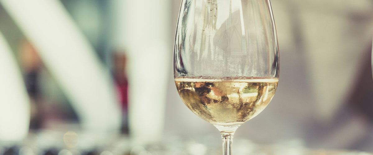 Chardonnay: Glas Weißwein im Gegenlicht, weicher Hintergrund