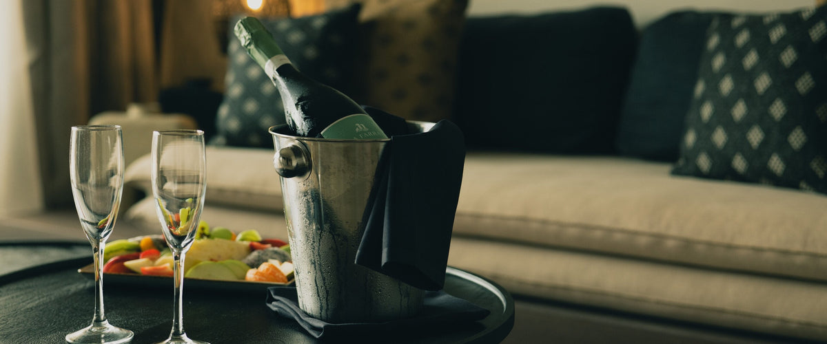 Crémant: Flasche im Kühler, zwei Flöten, Sofa