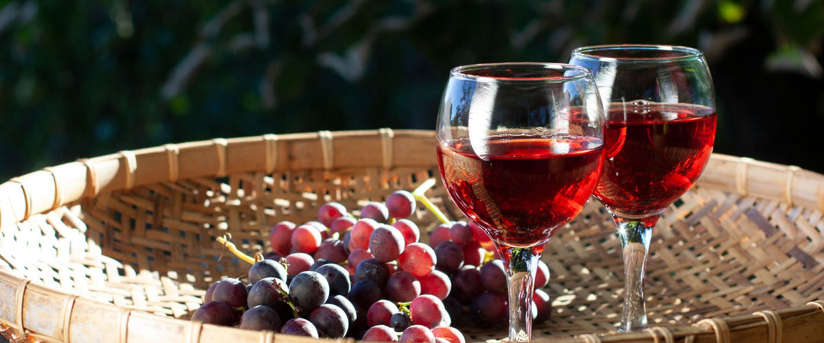 Grenache & Garnacha: Rote Weingläser auf einem Korb mit Trauben