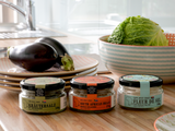 Drei Gläser Cape West Coast Salz, darunter Fleur de Sel, mit Aubergine und Wirsing in einer Küche