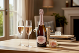Flasche Kleine Zalze Brut Rosé MCC mit zwei Sektgläsern auf einem Tisch im Wohnzimmer
