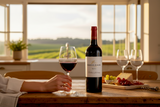 Flasche Kleine Zalze Cellar Selection Merlot mit Rotweingläsern und Käse an einem Fenster mit Blick auf Weinberge