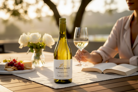 Flasche Kleine Zalze Cellar Selection Sauvignon Blanc mit einem Glas Weißwein und Blumen auf einem Gartentisch