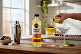 Flasche Punch Club Pornstar Martini neben Shaker und Cocktailglas mit Maracuja auf einer Küchenarbeitsplatte