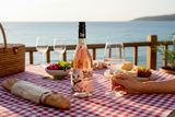 Flasche What the Duck Grenache Syrah Rosé beim Picknick auf rot karierter Decke am Meer