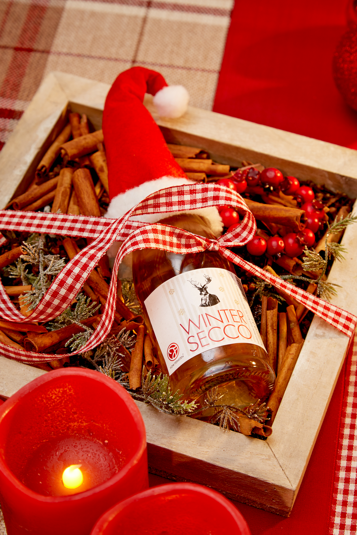 Piccolo Wintersecco mit Zimt und Nelke von Vom Feinsten mit Weihnachtsmütze in einer Holzkiste mit Zimtstangen